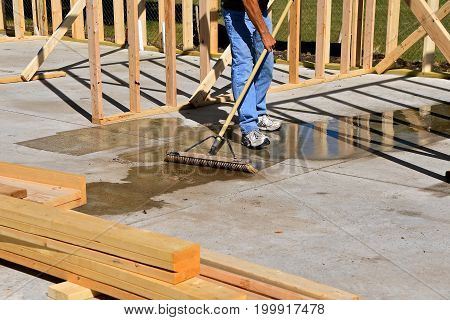 The  cement floor of a construction building site is being swept to remove a water puddle after a rain shower