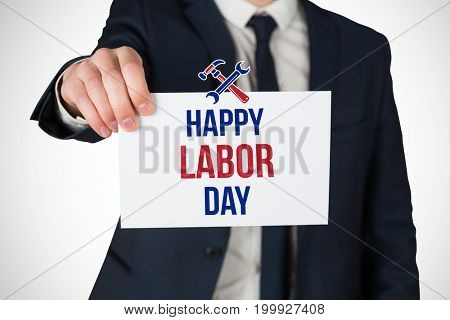Businessman showing card to camera against digital composite image of happy labor day text with tools