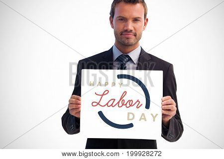 Serious businessman holding a white card against digital composite image of happy labor day text with blue outline
