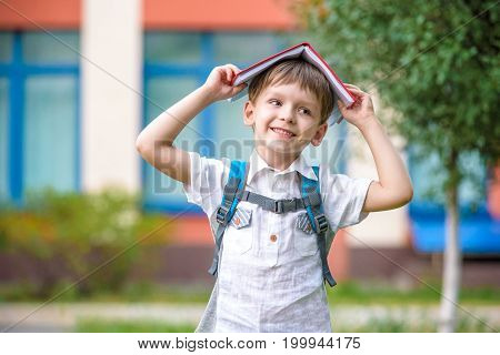 Child With Book On His Head Outdoors