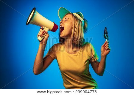 Beautiful Female Half-length Portrait Isolated On Blue Neon Lights Studio Background. Woman In Green