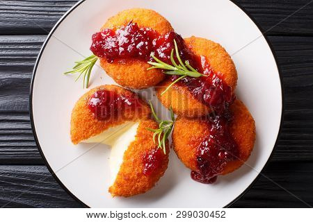 Gourmet Appetizer Camembert In Breading Served With Cranberry Sauce And Rosemary Close-up On A Plate