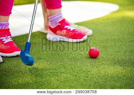 Miniature Golf Outdoor. Little Girl Hit Ball In The Mini Golf Course.
