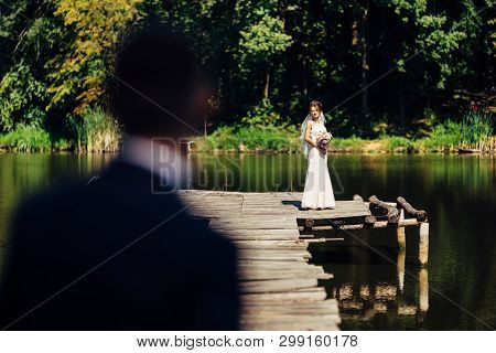 Portrait Of An Amazing Wedding Couple. They Are Standing Near The Forest, On A Wooden Bridge, Above 