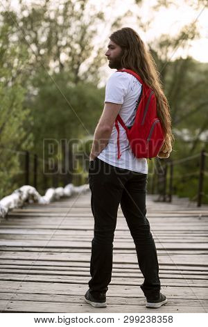 Male With Tshirt And Backback Is Standing On A Wooden Bridge In The Spring