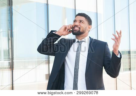 Cheerful Businessman Talking On Phone And Celebrating Good News And Success. Young Latin Man In Form