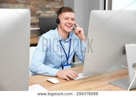 Technical Support Operator Working With Headset And Computer At Table In Office