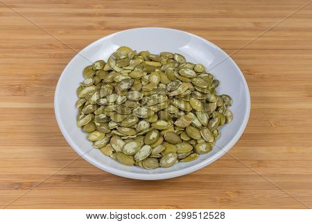 Pumpkin Seeds Peeled From Shells On The Whiote Saucer On A Wooden Surface
