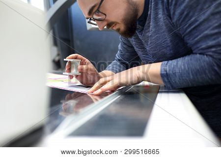 The Printer At The Stage Watches The Print Quality Through A Magnifying Glass.