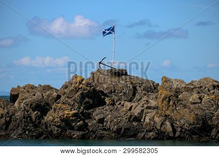 Scottish Saltire Flag And Rusting Anchor At Portpatrick Harbour In Southern Scotland