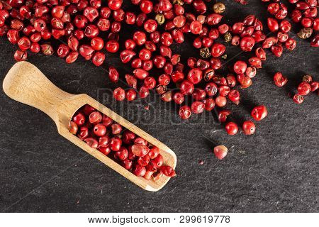 Closeup Of Lot Of Whole Peruvian Pink Pepper With Wooden Scoop Flatlay On Grey Stone