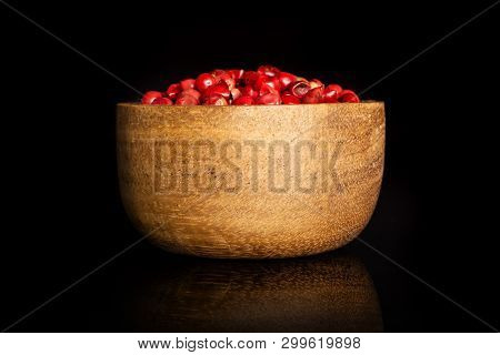 Lot Of Whole Peruvian Pink Pepper In A Wooden Bowl Isolated On Black Glass