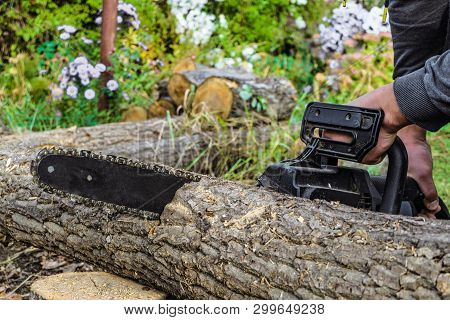 Sawing A Wooden Log With An Hand Electric Chain Saw