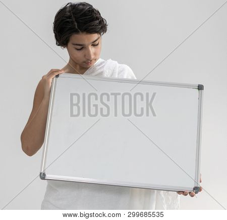 Teenage boy wearing Ihram for Hajj holding copy space board