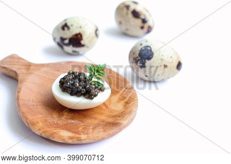 Delicious Black Sturgeon Caviar On A Quail Egg With Rosemary On The Wooden Plate And Fresh Quail Egg