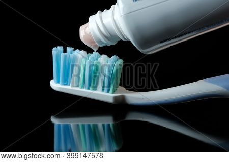Light Pink Paste Is Squeezed Out Of The Tube Onto The Toothbrush On Black Background Close-up Macro 