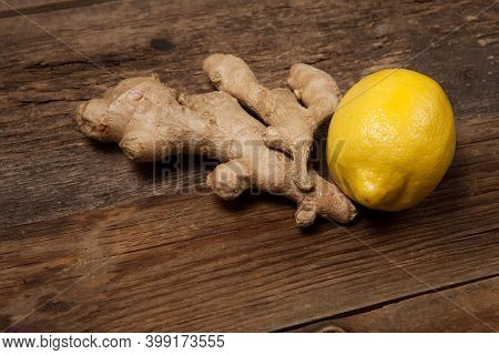 Close Up Of Fresh Ginger Root And Lemon On Wooden Table