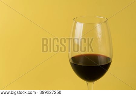 Glass Of Red Wine On A Yellow Background. Close-up View. Isolated Yellow Background