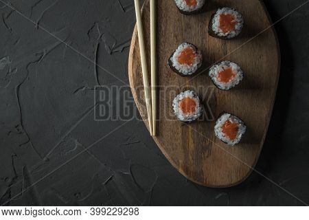 Classic Sushi With Salmon On A Wooden Board On A Stone Black Table. Nearby Are Chinese Sticks. Top V