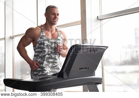 Muscular Athletic Bodybuilder Fitness Model Running Treadmill Gym Near Big Window Jogging Stationary