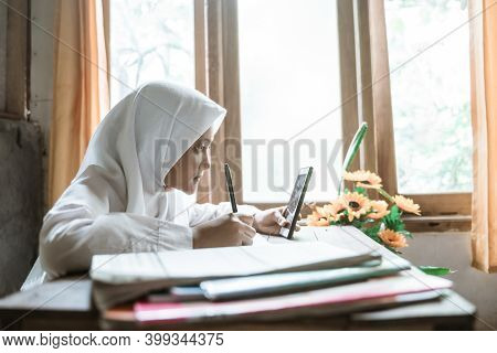 Indonesian Schoolgirl Studying Homework During Her Online Lesson