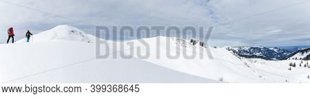 Senior Couple Is Snowshoe Hiking In Alpine Snow Winter Mountains Panorama. Allgau, Bavaria, Germany.