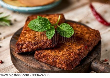 closeup of some tofu fillets on a round wooden tray, on a table