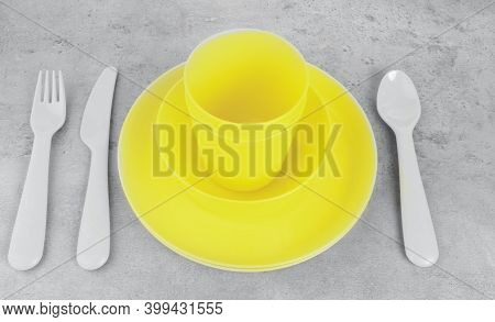 Picnic Yellow Cutlery Utensils, Plates, Cups, Fork, Spoon And Knife On Grey Background