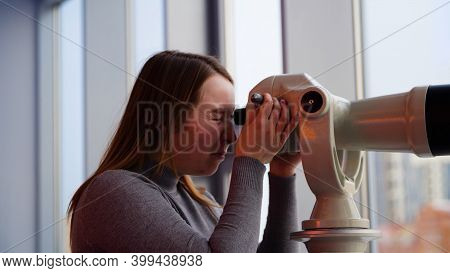 Young Woman Looks Through Stationary Binoculars. Media. Beautiful Woman Looks Through Binoscope On O