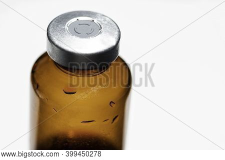 A Macro Shot With Selective Focus Of An Amber Color Vaccine Injection Bottle Set On Plain White Back
