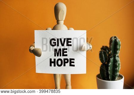 The Wooden Man Holds A White Sign With The Text Give Me Hope In His Hands. The Content Of The Letter