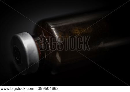 A Macro Shot With Selective Focus Of An Amber Color Vaccine Injection Bottle Set On Plain Black Back