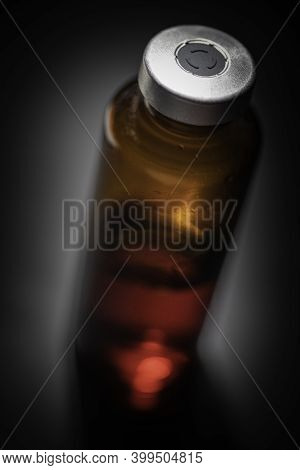 A Macro Shot With Selective Focus Of An Amber Color Vaccine Injection Bottle Set On Plain Black Back