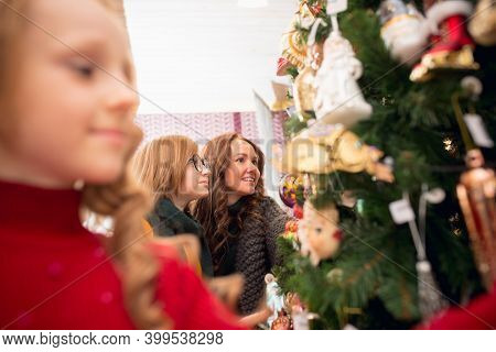 Christmas Tree. Smiling Family, Mother And Kids Looking For Home Decoration And Holidays Gifts In Ho
