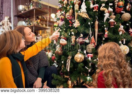 Christmas Tree. Smiling Family, Mother And Kids Looking For Home Decoration And Holidays Gifts In Ho