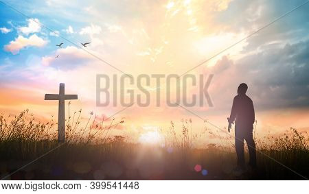 Praise And Worship Concept: Silhouette Human Standing And The Cross On Meadow Sunset Background