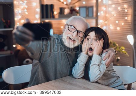 Grandfather And Grandson Are Taking Selfie At Night At Home.