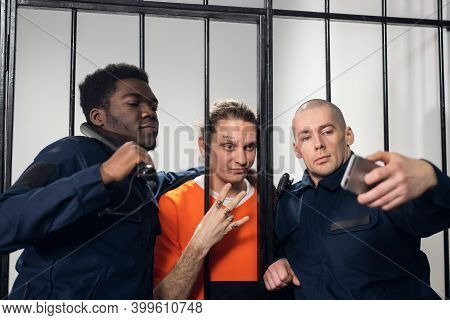 Actors On The Set Of A Movie About Prison Make A Funny Selfie In A Prison Cell Against The Backgroun
