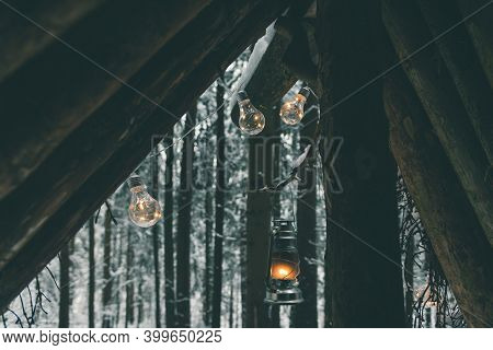 Garlands And Kerosene Lamp Hanging On Survival Shelter In Winter Forest
