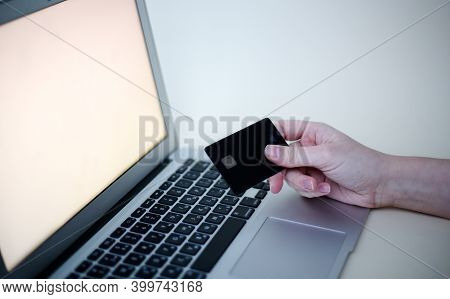 Hand Of A Woman Who Holds A Credit Card Near The Laptop