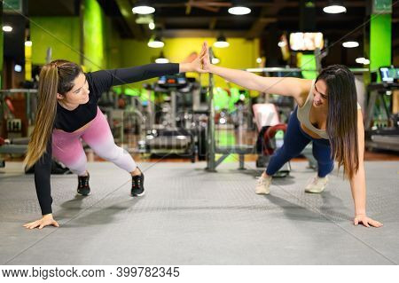 Two Sporty Women Doing High Five While Workout Push Up Exercise In Gym. High Quality Photo