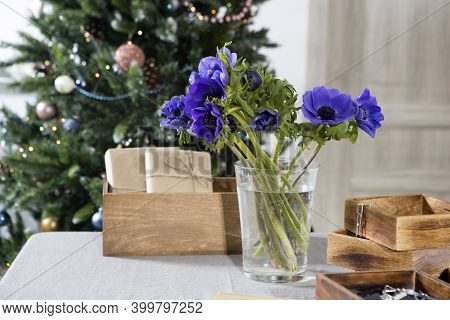 A Bouquet Of Blue Anemones In A Glass Vase On A Table Covered With A Gray Tablecloth In Front Of A C