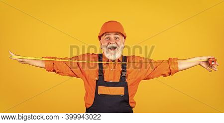 Confident Mechanic. Happy Carpenter. Handyman Measuring Wall. Senior Builder Tape-line For Measure. 