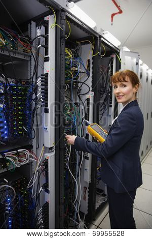 Happy technician using digital cable analyzer on server in large data center