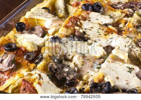 Homade vegetarian lasagna casserole topped with sliced mushrooms olives and artichoke hearts