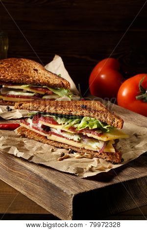 Two pieces of club sandwich on old paper with big cutting board