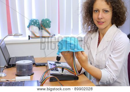 Medical worker holding a special hat for electroencephalography