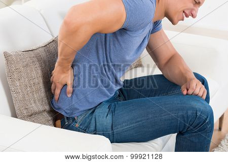 Man On Sofa Suffering From Backpain