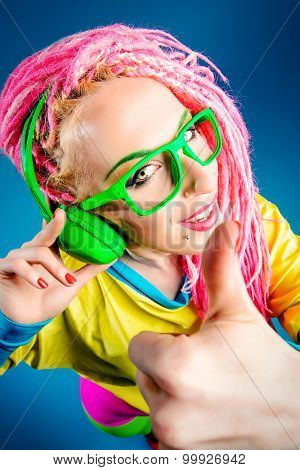 Ultra trendy DJ party girl in bright clothes, headphones and with bright dreadlocks. Disco, party. Show business. Bright fashion.