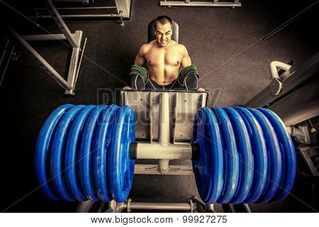 Muscular man weightlifter doing leg presses in gym. Sports.
